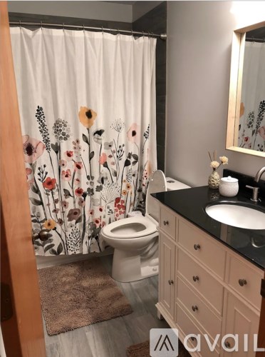 A bathroom with a floral shower curtain and a white toilet.