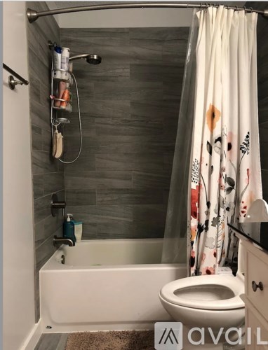 A bathroom with a white tub and a shower curtain with a floral pattern.