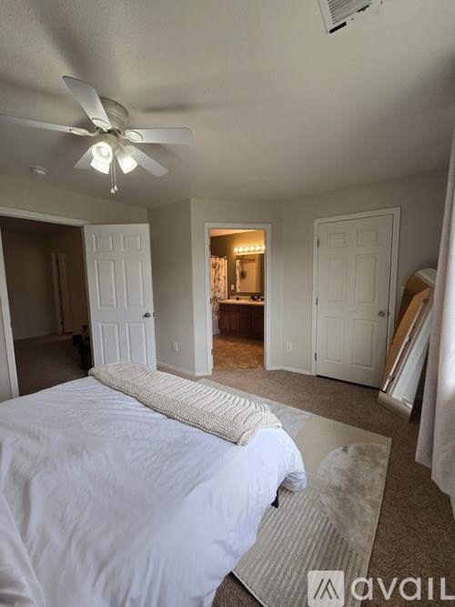 A bedroom with a large bed and a ceiling fan.