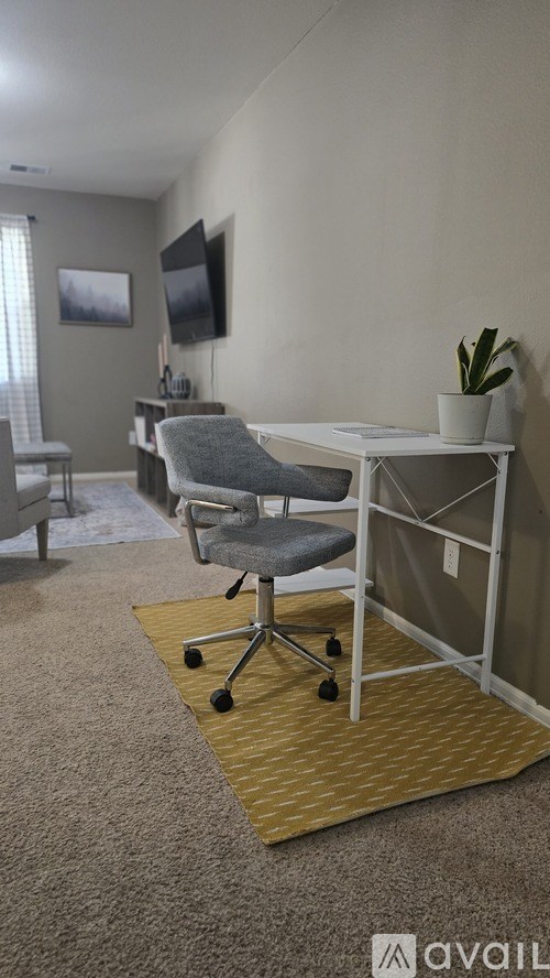 A room with a grey chair and a white desk.