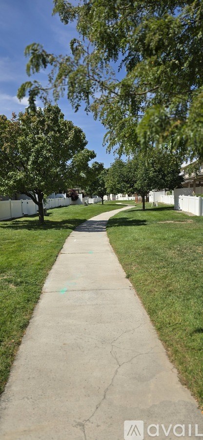A concrete pathway leads through a grassy area with trees on either side.