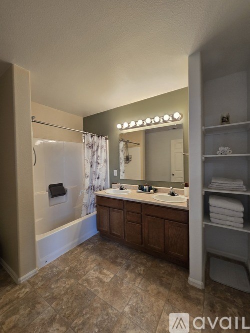 A bathroom with a vanity, mirror, and shower.