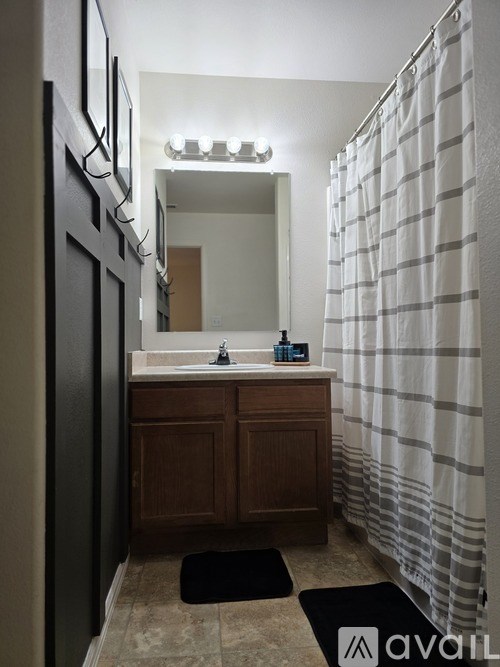 A bathroom with a sink, mirror, and shower curtain.