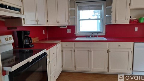 A kitchen with red walls and white cabinets.