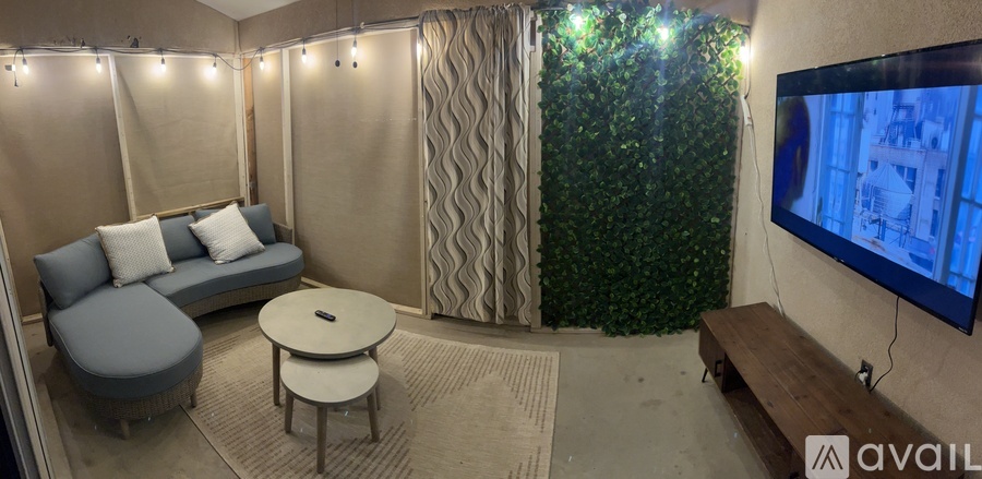 A living room with a grey sofa, a round table, a television and a green plant in the background.