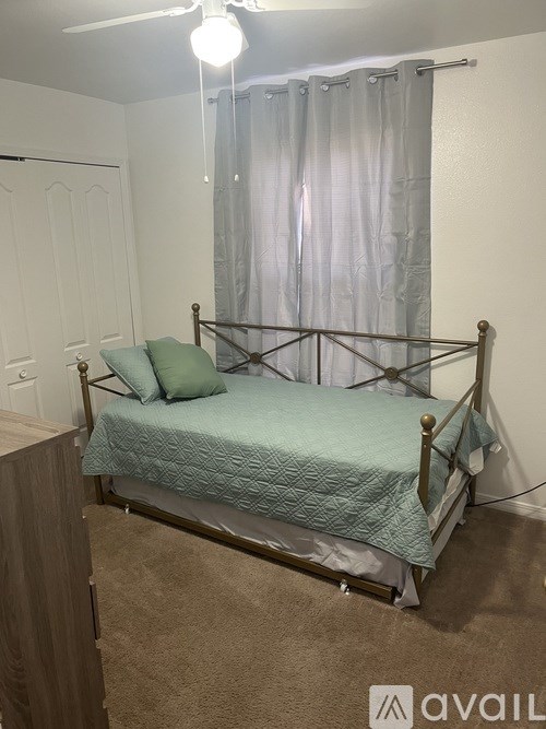 A bed with a green bedspread and a metal frame.