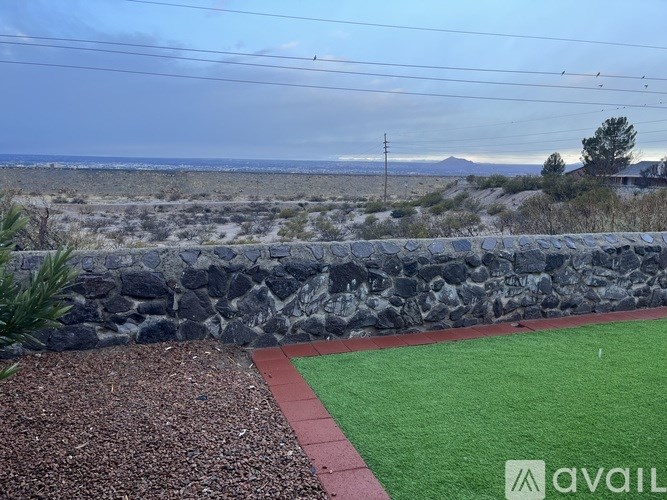 A stone wall with a red and green striped path in front of it.