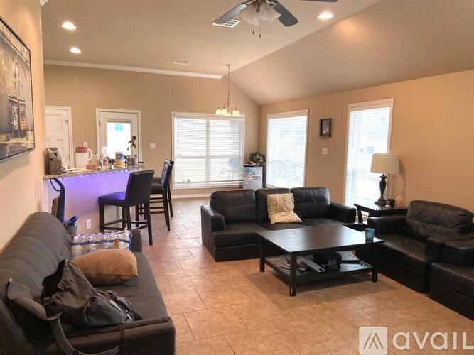 A living room with black furniture and a ceiling fan.