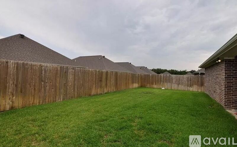 A backyard with a wooden fence and a green lawn.