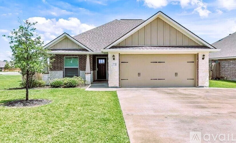 A house with a garage and a tree in front.