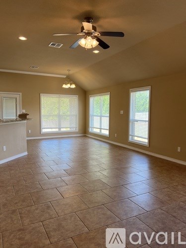 A spacious room with a ceiling fan and tile flooring.