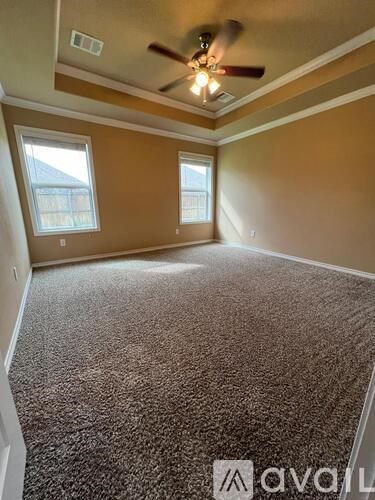 A room with a carpeted floor and a ceiling fan.