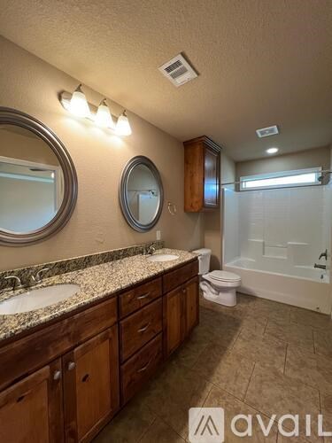 A bathroom with wooden cabinets and granite countertops.