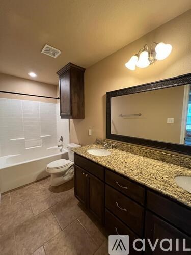 A bathroom with a toilet, sink, and mirror.