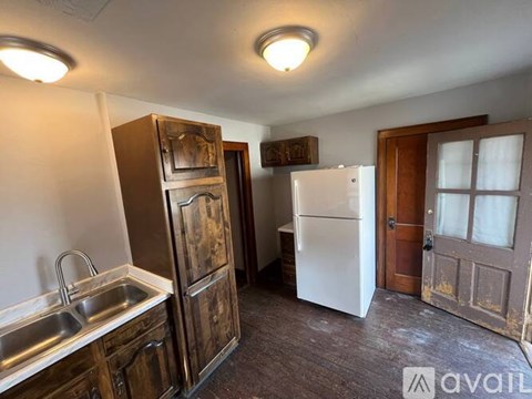 A kitchen with a sink, refrigerator, and wooden cabinets.