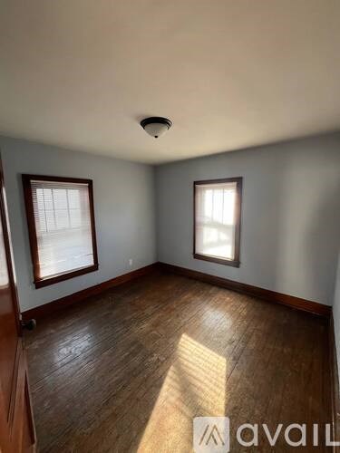 A room with wooden floors and two windows.