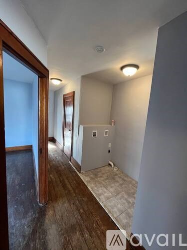 A hallway with a wooden floor and white walls.