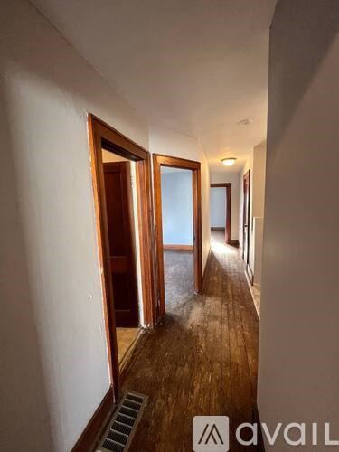 A hallway with wooden floors and white walls.