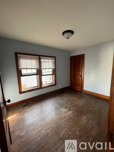 A room with wooden floors and a window with blinds.