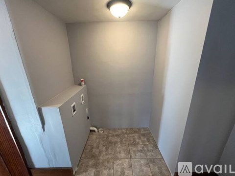 A small, empty room with a tiled floor and a single light fixture on the ceiling.