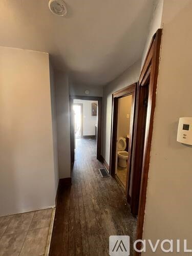 A hallway with a toilet visible through the door.