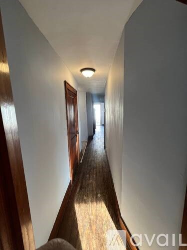 A long hallway with wooden floors and white walls.