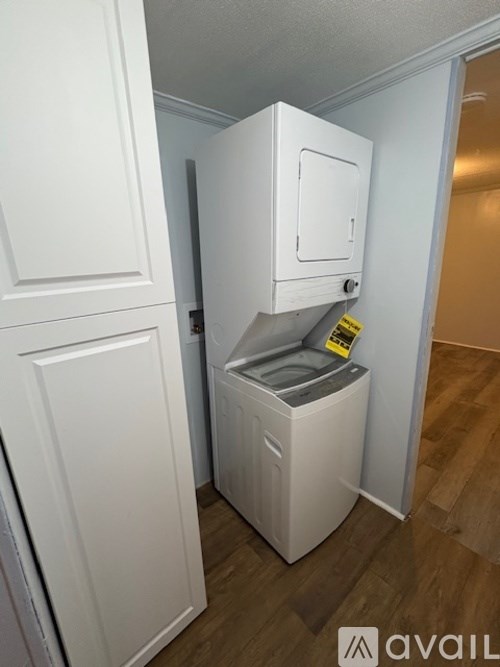 A small white laundry machine sits in a narrow hallway.