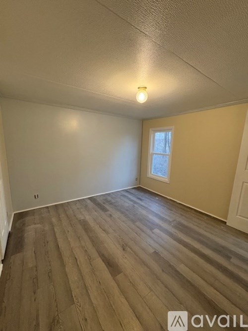 A room with wooden flooring and a window.