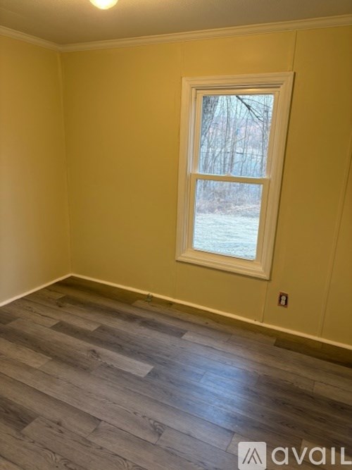 A room with a window and wooden flooring.