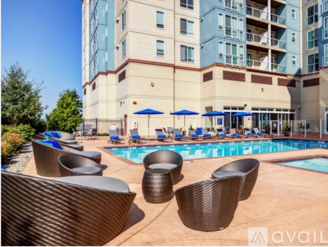 A pool area with chairs and umbrellas in front of a multi-story building.