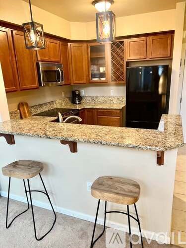 A kitchen with a granite countertop and bar stools.