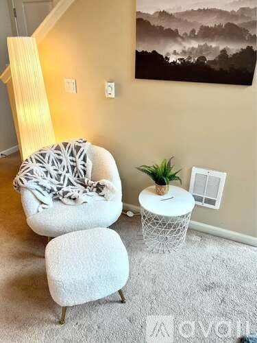 A chair with a white cushion and a small white table with a plant on it.