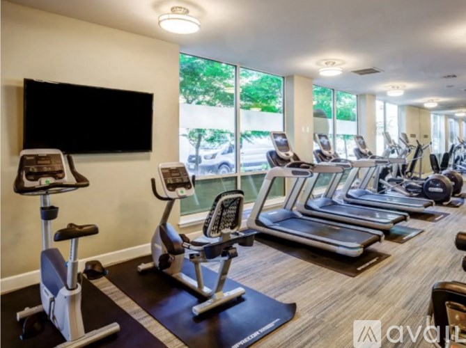 A gym with treadmills, exercise bikes, and a television.