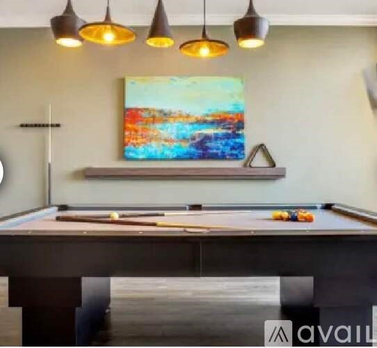 A pool table with a painting hanging above it.