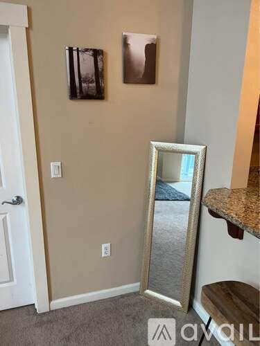 A mirror is leaning against a wall with two picture frames above it.