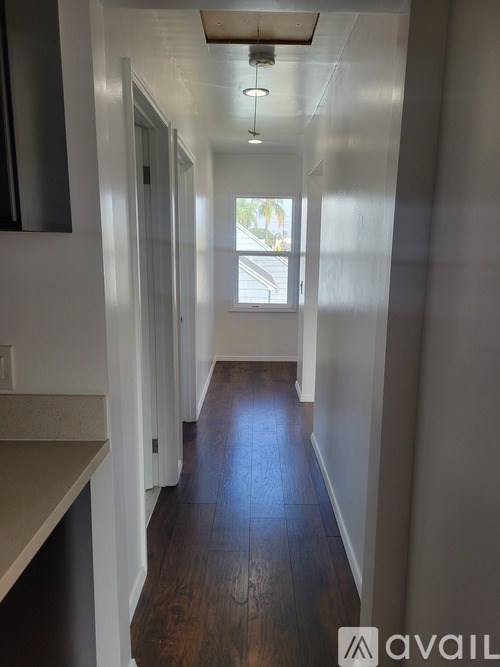 A long hallway with wood floors and white walls.