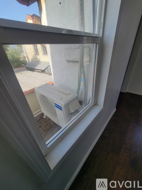 A white container is sitting on a wooden deck outside a window.