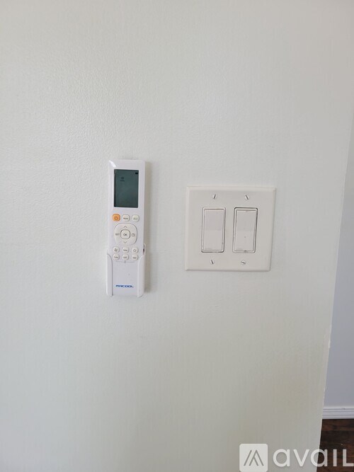 A white thermostat and light switch plate on a white wall.