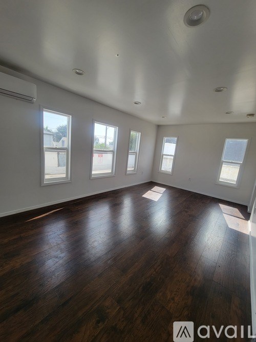 A room with wooden floors and windows on the wall.
