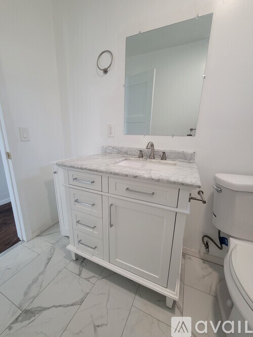 A bathroom with a marble countertop and white cabinets.