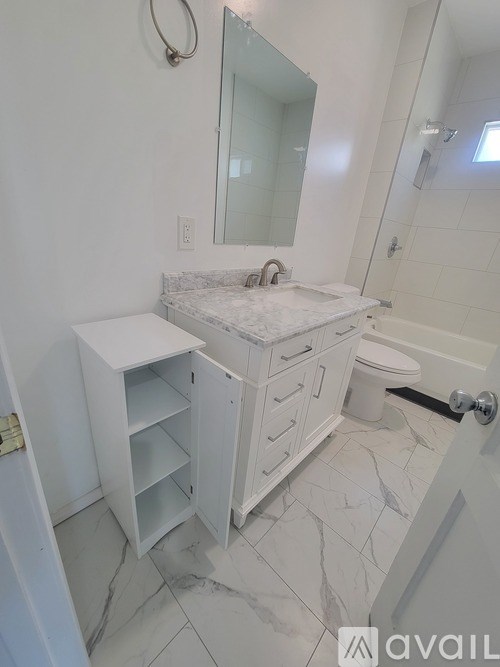 A bathroom with a marble countertop and a white vanity.