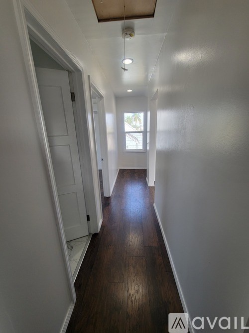 A long hallway with white walls and wood flooring.