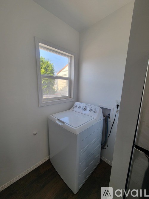 A white hot tub sits in a corner of a room with a window.