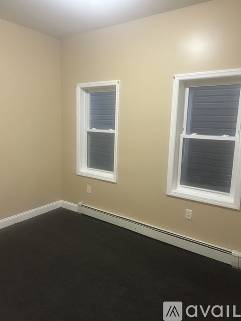 A room with two windows and a black floor.