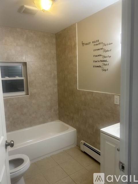 A bathroom with a toilet, a bathtub, and a towel rack.