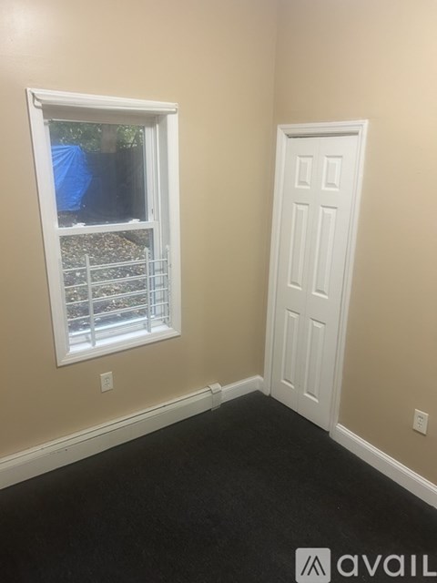 A room with a white door and a window with a view of a yard.