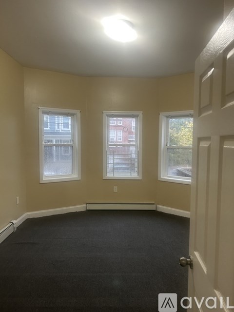 A room with a carpeted floor and two windows.