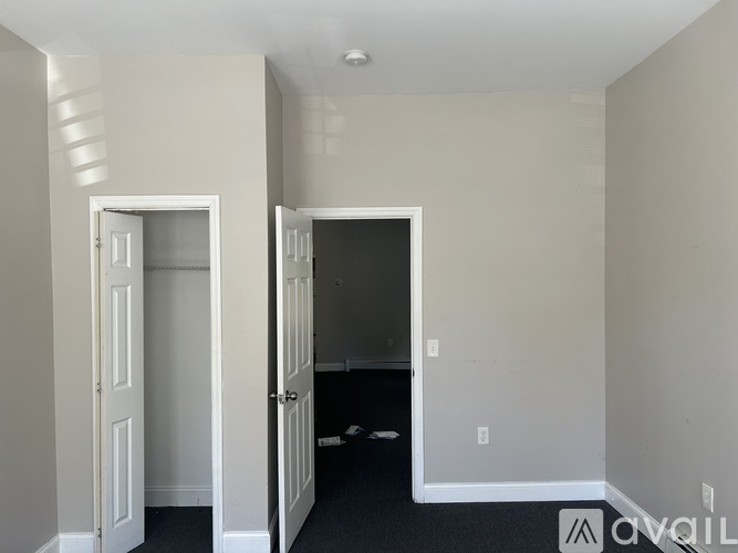 A room with two doors, one open, and a carpeted floor.
