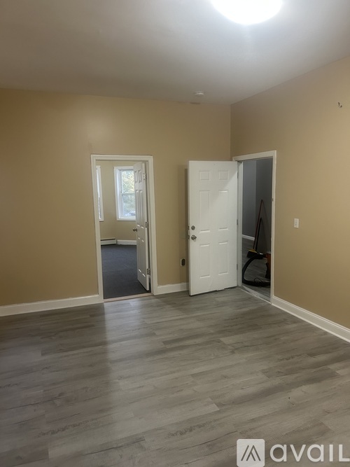 A room with a white door and a window with a view of trees.