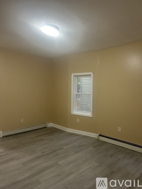 A room with a window and wooden flooring.